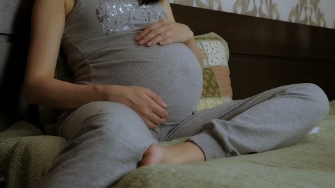Pregnant girl stroking her stomach.