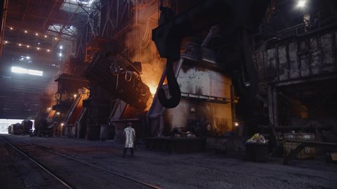 Iron foundry. Loading scrap metal into the converter furnace. The steelworker stands and leads the process.