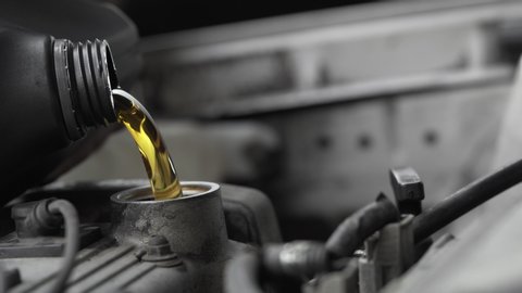 Pouring fresh new clean synthetic oil into car's engine
