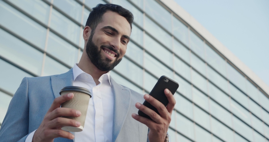 Man Entrepreneur Drinking Coffee uses Smartphone. Businessman Typing message Looking at Phone screen standing near Huge Glass Building  Royalty-Free Stock Footage #1036761011
