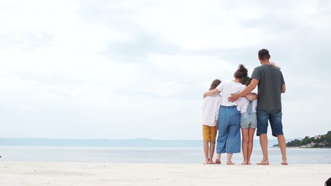 Happy family vacation. Parents and three children stand on the shores of the Mediterranean Sea. Light blue sea. Copyspace on the left