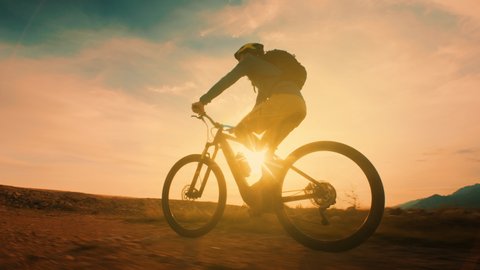 Low angle shot of a man cycling at sunset