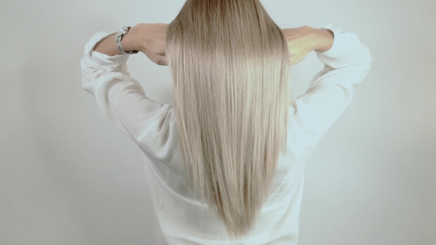 
Well-groomed, blond, long hair crumbles on a white background. Hair advertisement. Beautiful blonde hair view from the back. Hair after salon procedures | Shutterstock HD Video #1036764968