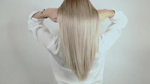
Well-groomed, blond, long hair crumbles on a white background. Hair advertisement. Beautiful blonde hair view from the back. Hair after salon procedures