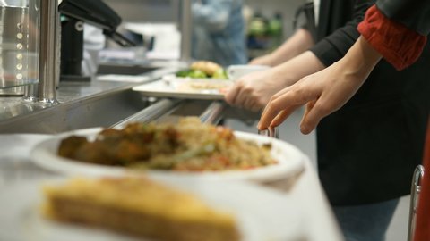 young woman hands move tray with dishes on white plates along special metal support in canteen slow motion closeup