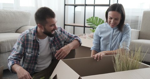 Couple unpacking carton box in new house