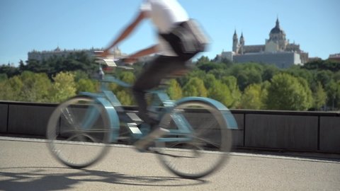Two people ride a bike in front of the Almudena Cathedral and the Royal Palace of Madrid