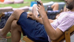 Young, happy man watching movie on smartphone in city park