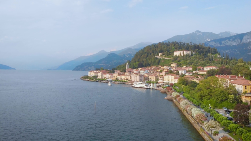 small cozy city is placed on coast of big lake or wide river between mountains, aerial calm view
