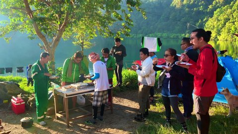 South Cotabato / Philippines - 08 11 2019: 14 seconds of footage with people eating outdoor into a bright day light with lake in the background – Redaktionelles Stockvideo
