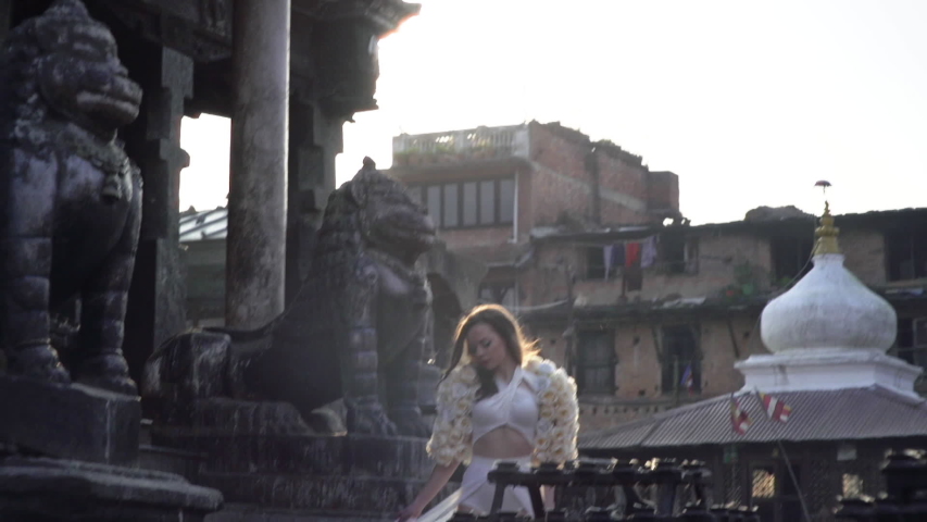 Beautiful brunette model walking through the ancient city in Nepal in a white dress.
