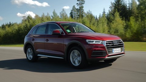 NOKIA, FINLAND - August 25, 2019: Red Audi Q5 drives on a country road during bright sunny day. The road is dry and safe. No other cars or people around. Some sun glare in the 2nd part of the footage.