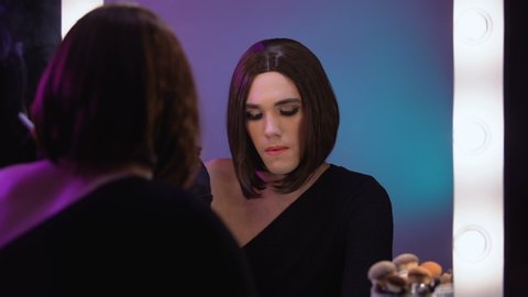 Luxury diva smoking looking sadly in mirror, misunderstood transgender celebrity
