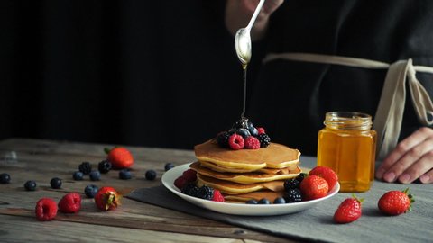 Pouring syrup over stack of fluffy buttermilk pancakes. Closeup view, slow motion footage. Seamless cinemagraph video