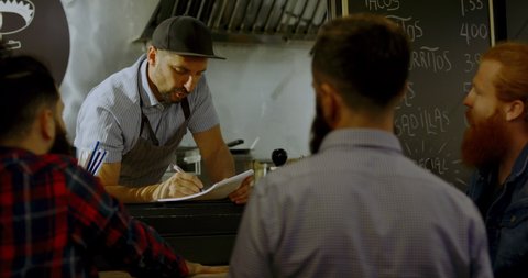 TRACKING Cheerful waiter taking order from customers at counter, Mexican street food served from a food truck. 4K UHD RAW graded footage