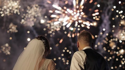Couple in love watching fireworks. Fireworks on a black background. Silhouette of a couple on fireworks background. Newlyweds