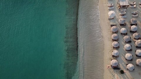 Mykonos Island Greece. Sandy Beach Top Down Aerial View. Sunshade Parasols and Clear Aegean Sea Water