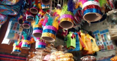 Colorful noise making toy made of feathers and paper, hanging in a traditional Guatemalan fair stand. Street vendor with candies, crafts and toys. Ronron