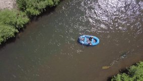 Birdseye drone follow camera looking down on a river raft floating towards rapids on a mountain river