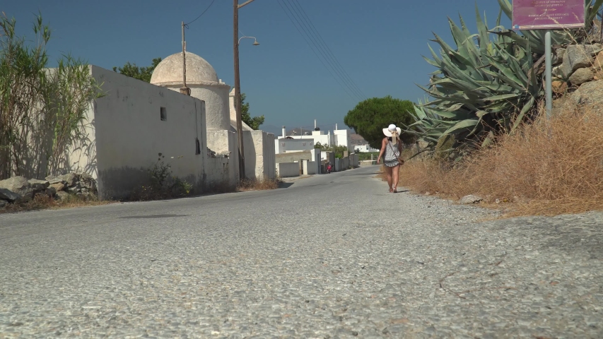 Young woman walking through classical Greek Village along the roadway
