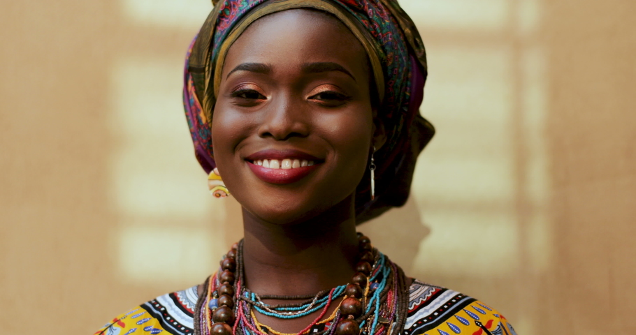Portrait of African American young charming and happy woman in the scarf on her head and traditional look laughing to the camera. Close up face  | Shutterstock HD Video #1036839071