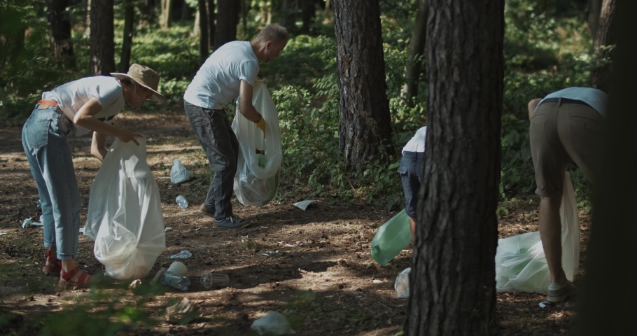 Friendly team of environment fighters cleanind the forest from consumption waste trash. Happy modern family support eco movement.