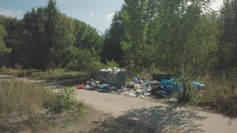 Kiev, Ukraine, August 2019: Elemental dump on the roadside near the outskirts of the city. Aerial view. Garbage is scattered on the green grass along the path. Pollution of the environment 