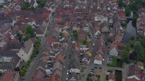 Aerial view of the old town of Kenzingen in Germany on a cloudy day in the afternoon. Tilt down with zoom in over the old town.