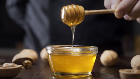 Chef dips wooden honey stick to the glass bowl with liquid honey, cooking with honey, sweet meals with natural ingredients, healthy food, Full HD Prores 422 HQ