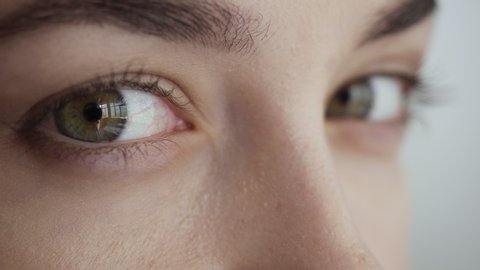 Close-up view on woman blinks and looks away. Green yes without makeup.