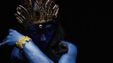 Indian goddess in a dark room is dancing and moving her hands, close up