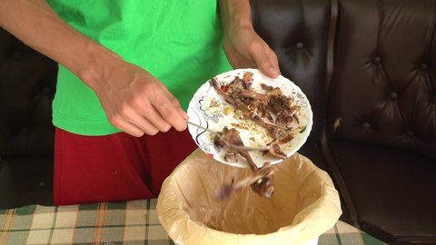 Food Waste at Thanksgiving. A man throws meat scraps and chicken bones into a bin. Food waste reduction. Sorting of household waste, composting, recycling, zero waste