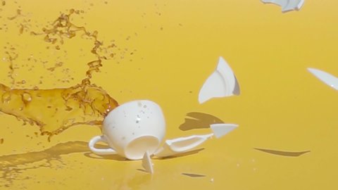 Cup of coffee falling and shattering, bad luck in the morning, slow motion, yellow background
