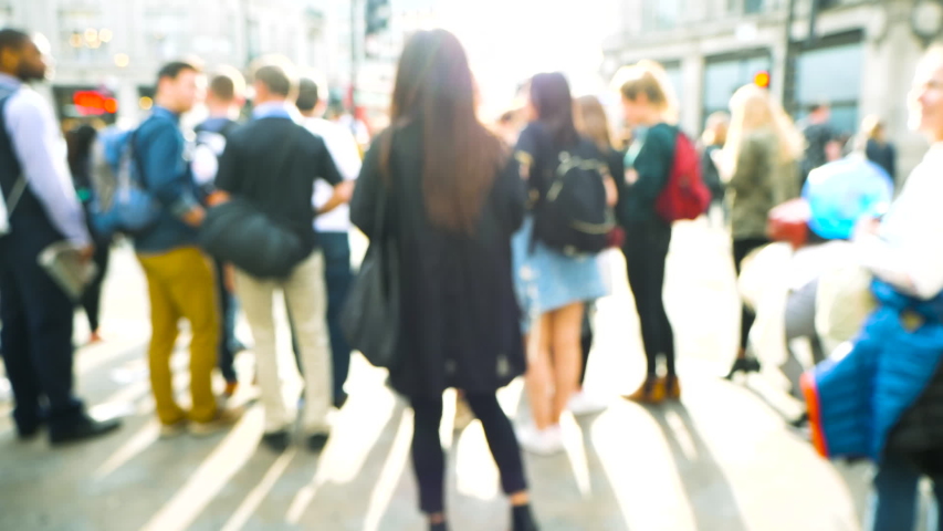 Rear view of blur defocused silhouettes of pedestrians people walking in slow motion on Oxford Circus interchange between the Bakerloo, Central and Victoria lines waiting to cross the street