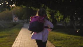 Little girl with a backpack run to school. School and kindergarten education concept. Back view, slow motion and steadicam video.