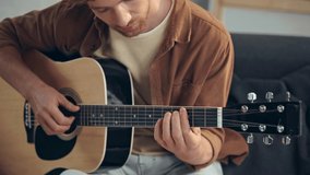 guitarist playing acoustic guitar on couch