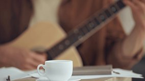 selective focus of man playing acoustic guitar near coffee cup