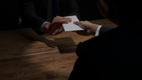 Businessman giving money in white envelope to partner in dark room for corruption and bribery concepts