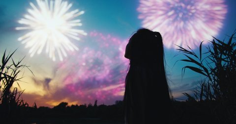 Young female near a lake watching fireworks. Sunset. Stockvideo
