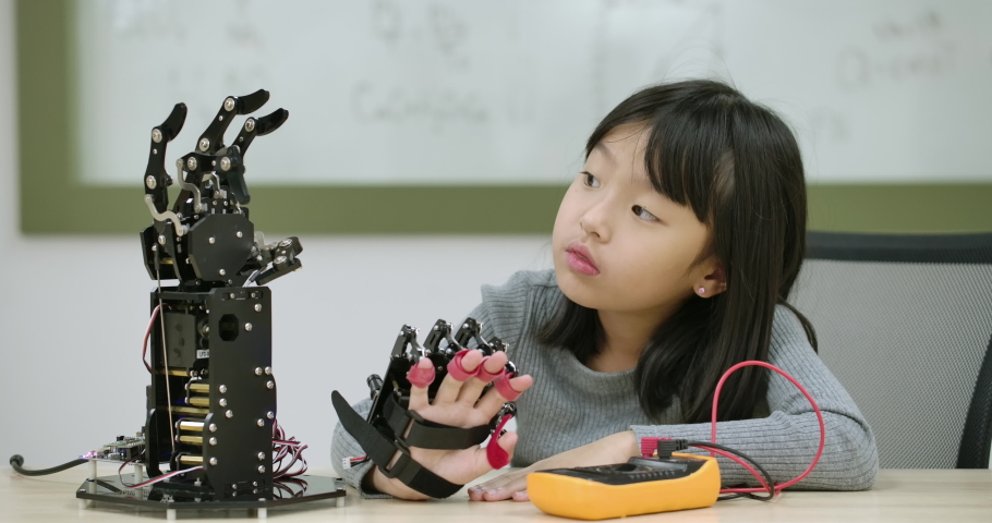 Little asian girl creates movement for mechanical robotic hand in school laboratory. Educational Technology Concept. Royalty-Free Stock Footage #1036878425