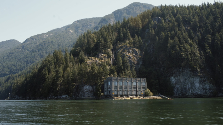 Wide shot of Buntzen Powerhouse from moving boat in the morning - Vancouver, Canada