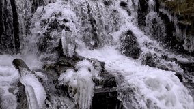 Flowing stream, non-freezing forest waterfall in winter. Water falls from height and cascades flows down, boils and breaking on stones slow motion, beautiful natural landscape, close-up stock video