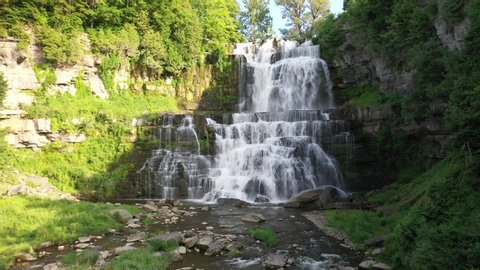 Aerial video of Chittenango Falls in Upstate New York. Flying low over river with slow tilt up while approaching waterfall cascade.