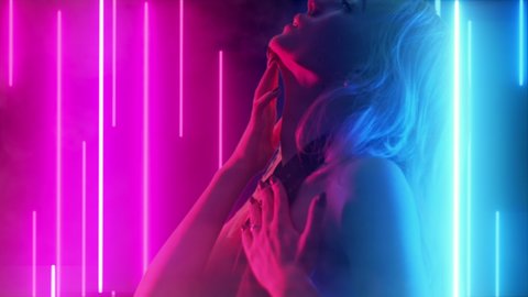 Girl Dressed In Black Is Dancing Slowly In Neon Lights. Perfect Female Body With Neon Stripes On The Background In The Night Club. Fashion Art Video
