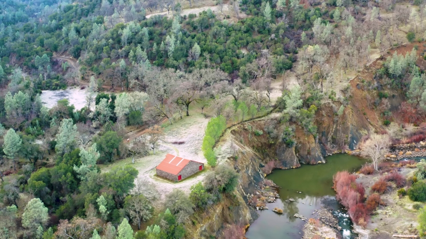 Aerial View Over Beautiful Autumn Mountain Landscape with River. Lonely House Among Orange Green trees in  forest. Mountain range in the background. Holidays, travel. Carpathians, 