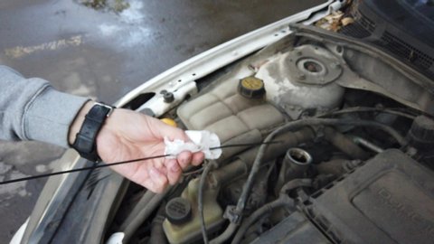 Car oil fill. Checks the car oil level with a dipstick. Replacing and pouring fresh oil into engine at maintenance repair service station