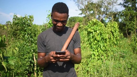 an average African male enjoying the technology, wireless modern bank payment terminal. Handsome farmer Shopping online with card. Mobile payment. Online shopping concept.