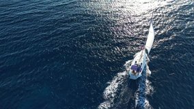 Aerial drone birds eye view video of beautiful sail boat cruising in the deep blue Aegean sea, Greece