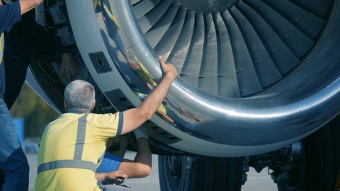 Aircraft Mechanics and Engineers  Diagnose and repairing jet engine through open hatch. Airplane turbine repair