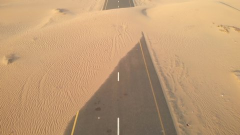 Aerial view from drone of abandoned desert roads covered with sand dunes in Dubai, United Arab Emirates